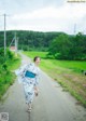 A woman in a blue and white kimono walking down a road.