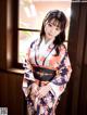 A woman in a kimono standing by a window.