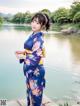 A woman in a blue kimono standing by a lake.