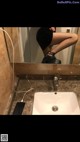 A woman in fishnet stockings is standing in a bathroom sink.