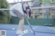 A woman bending over to pick up a tennis ball.