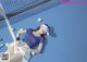 A woman laying on a tennis court next to a net.