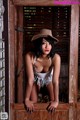 A woman in a cowboy hat leaning against a wooden door.