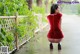 A woman in a red dress crouching down on a sidewalk.