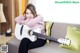 A woman sitting on a couch holding a white guitar.