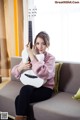 A woman sitting on a couch holding a white guitar.