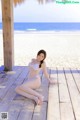 A woman in a white bikini sitting on a wooden dock.