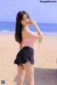 A woman standing on a beach next to the ocean.