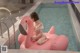 A woman sitting on an inflatable flamingo in a swimming pool.