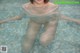 A woman in a white shirt is sitting in a pool.