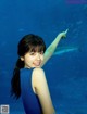 A woman in a blue dress pointing at a shark.