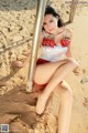 A woman in a red and white bikini sitting on a beach.