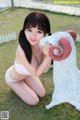 A woman in a bikini posing next to a statue of a ram.