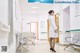 A woman in a white lab coat standing in a hospital hallway.