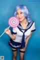 A woman in a sailor outfit holding a lollipop.