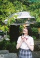 A woman in a school uniform holding an umbrella.