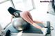 A woman is sitting on an exercise ball in a gym.