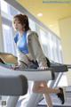 A woman is running on a treadmill in a gym.