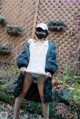 A woman wearing a face mask standing in front of a fence.