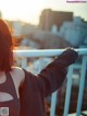 A woman standing on a balcony with her arms outstretched.