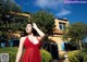 A woman in a red dress standing in front of a house.