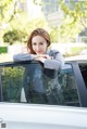 A woman leaning on the window of a white car.