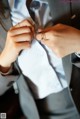 A woman in a gray suit adjusting her tie.