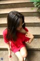 A woman in a red dress sitting on some steps.