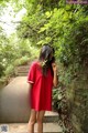 A woman in a red dress standing on some steps.