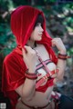 A woman in a red hooded outfit is posing for a picture.