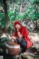 A woman in a red hoodie sitting on a rock with a basket.