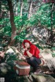 A woman in a red hoodie sitting on a rock with a basket.