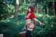 A woman in a red hooded outfit holding a basket in the woods.