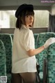 A woman in a white shirt and white gloves on a bus.