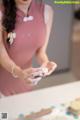 A woman in a pink dress is making cookies.