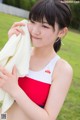 A woman in a red and white bathing suit holding a white towel.