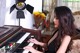 A woman in a black dress playing a piano.