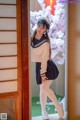 A woman in a sailor outfit standing in front of a door.