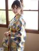 A woman in a kimono standing by a window.