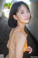 A woman in an orange bikini posing for a picture.