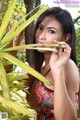 A woman in a colorful dress holding a palm leaf.