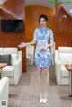 A woman in a blue and white dress standing in a room.