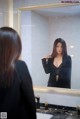 A woman standing in front of a mirror in a bathroom.