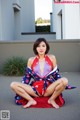 A woman in a red and blue kimono sitting on the ground.